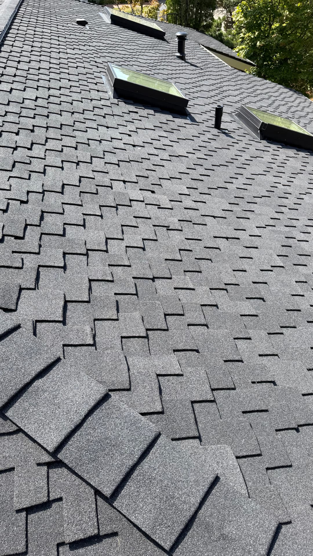 Multi-plane shingle roof with skylights and pipe vents after full replacement