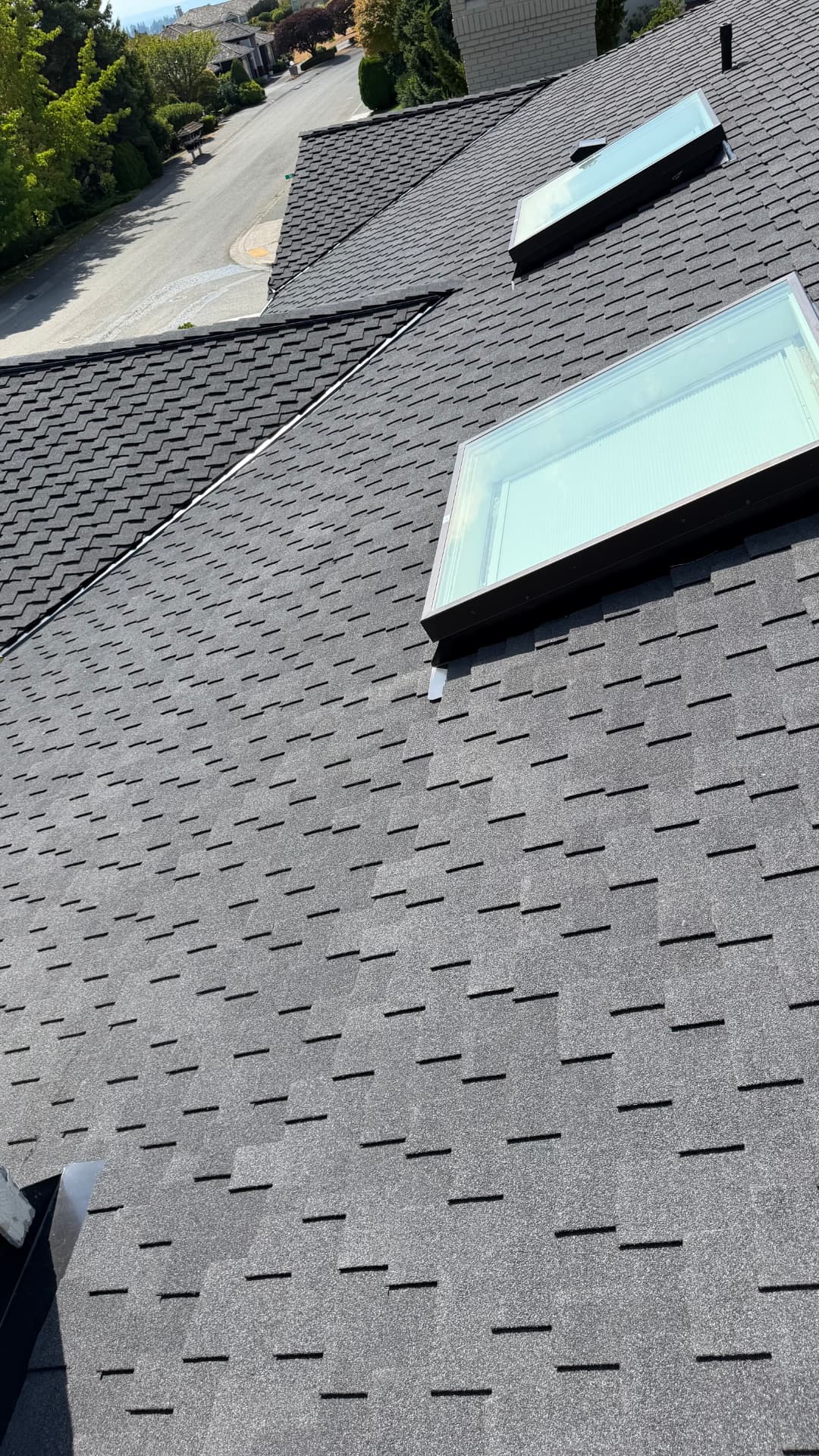 Two skylights set into a freshly installed charcoal shingle roof plane
