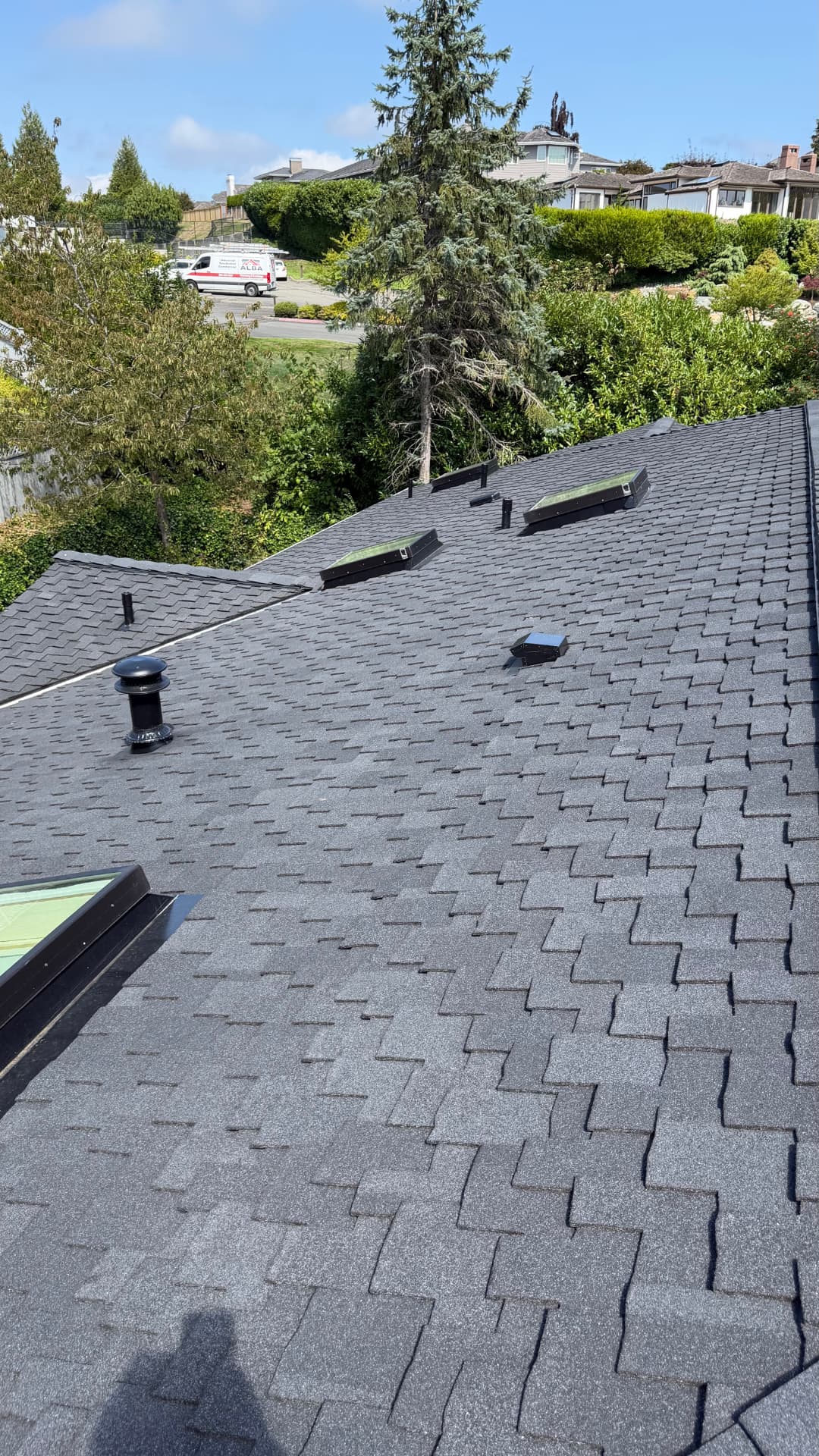 Completed roof replacement showing new vents, skylights and straight shingle courses